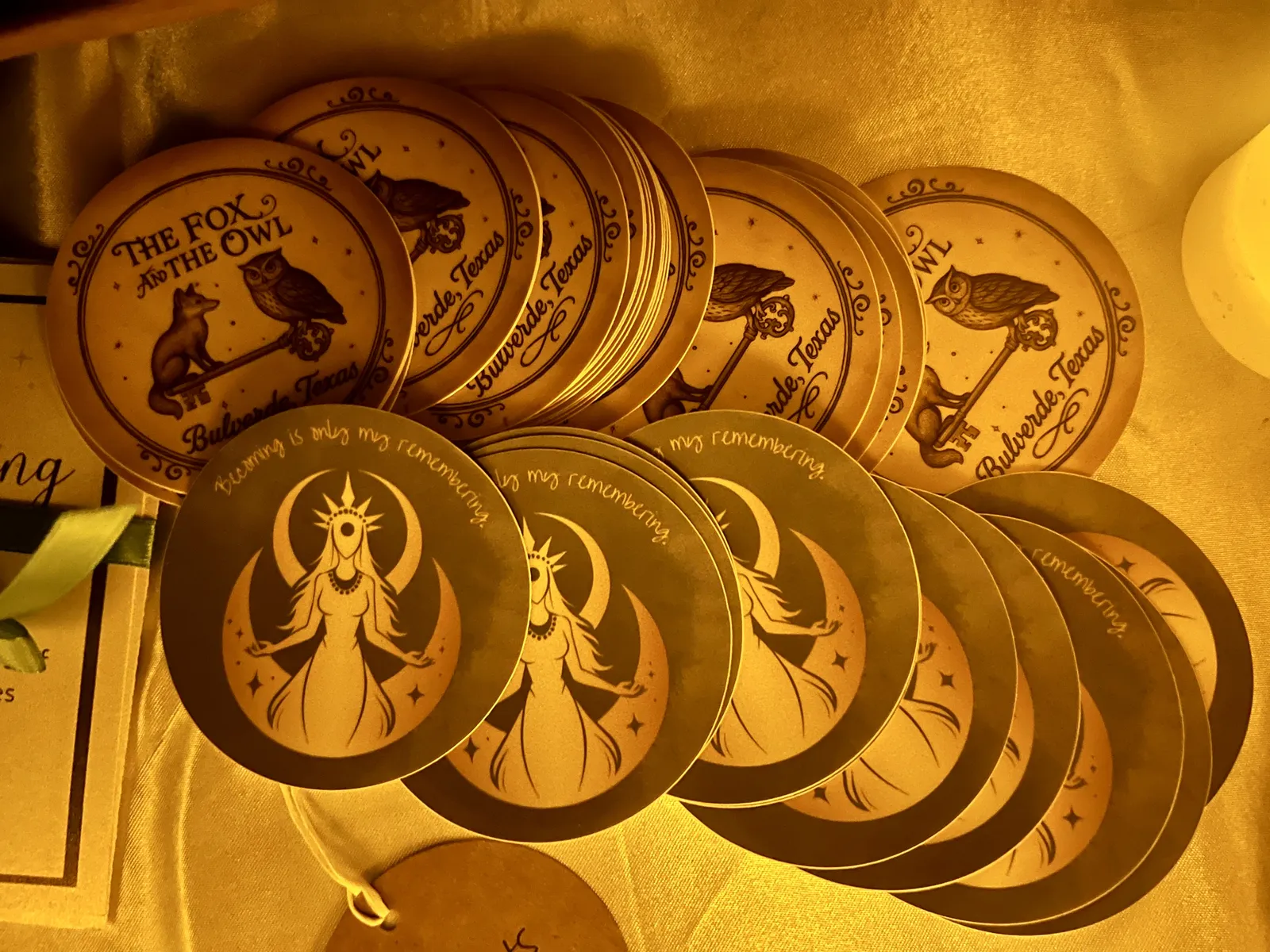 Round wooden favors stamped with The Fox and The Owl mark and the Becoming workshop mantra