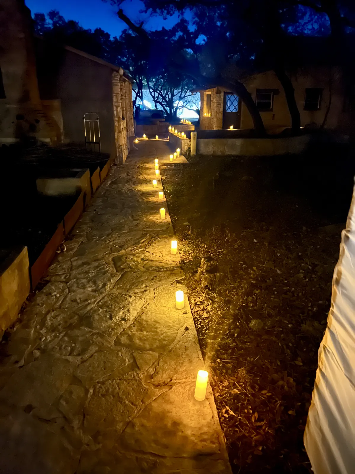 Candlelit stone pathway across The Fox & The Owl grounds at dusk, January 2026