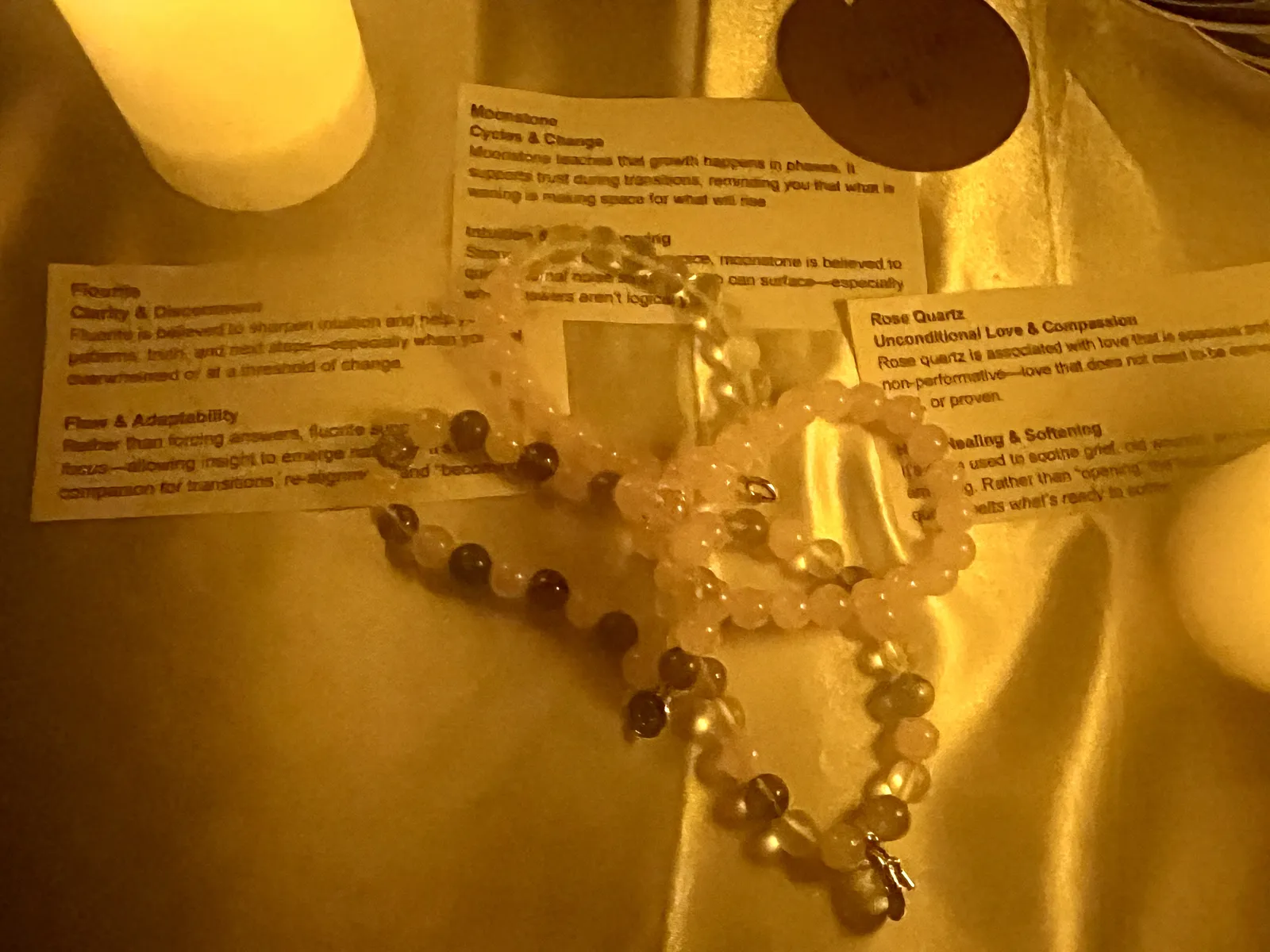 Crystal bracelets laid on workshop reading cards by candlelight