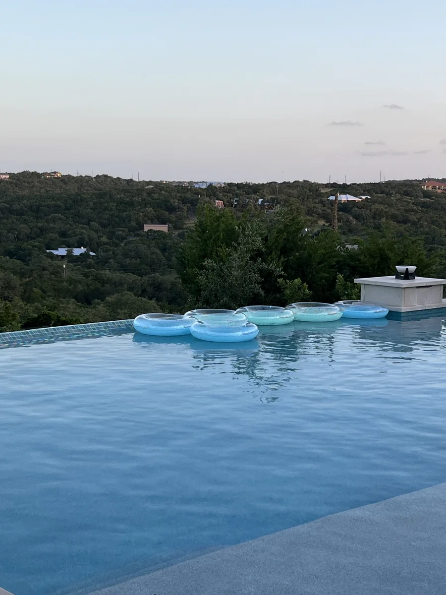 Floating rings resting on an infinity pool at dusk, overlooking the Hill Country